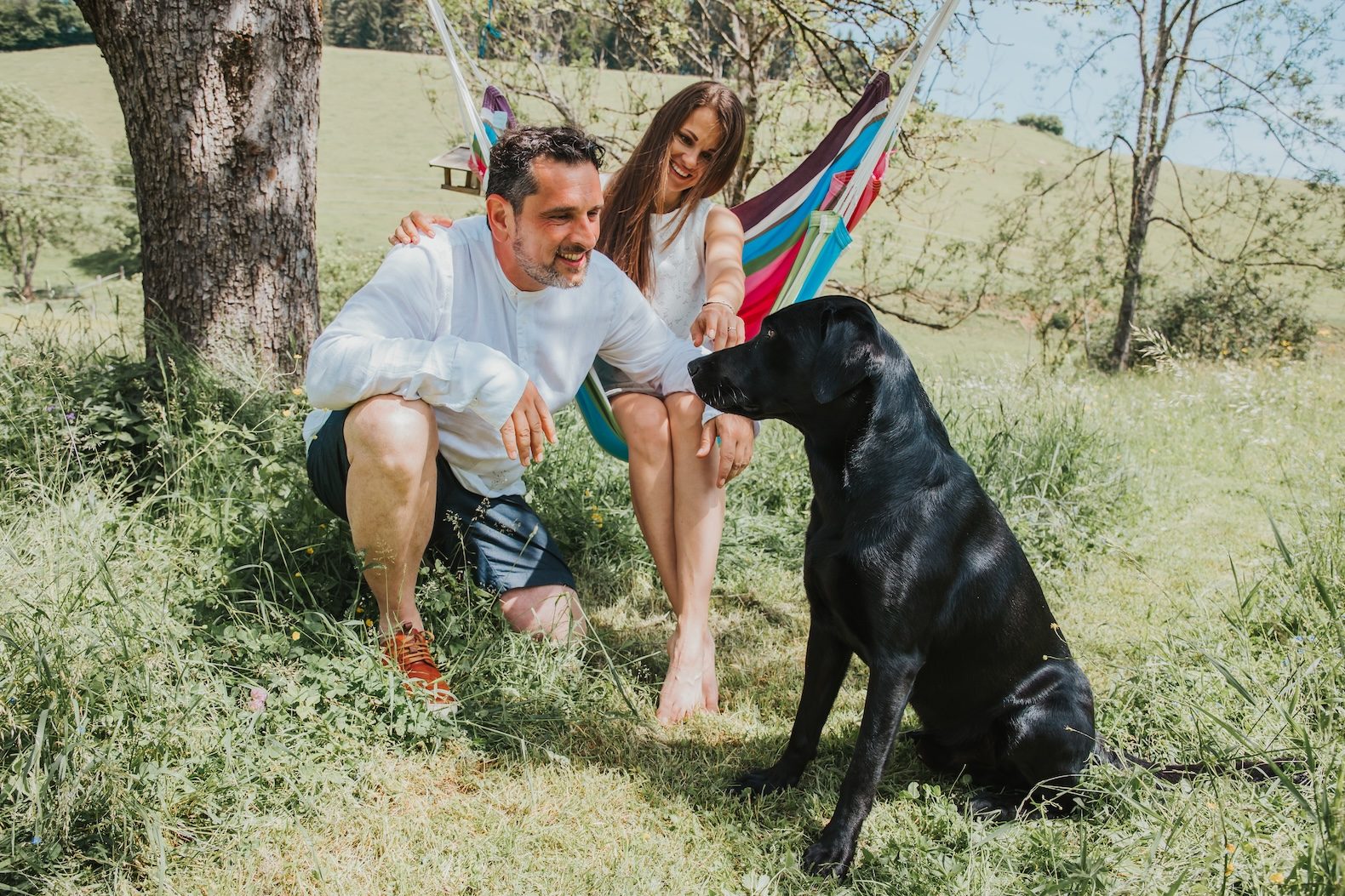 Melanie, Patrick und Labrador Kosmo auf einer Blumenwiese vor der Hängematte