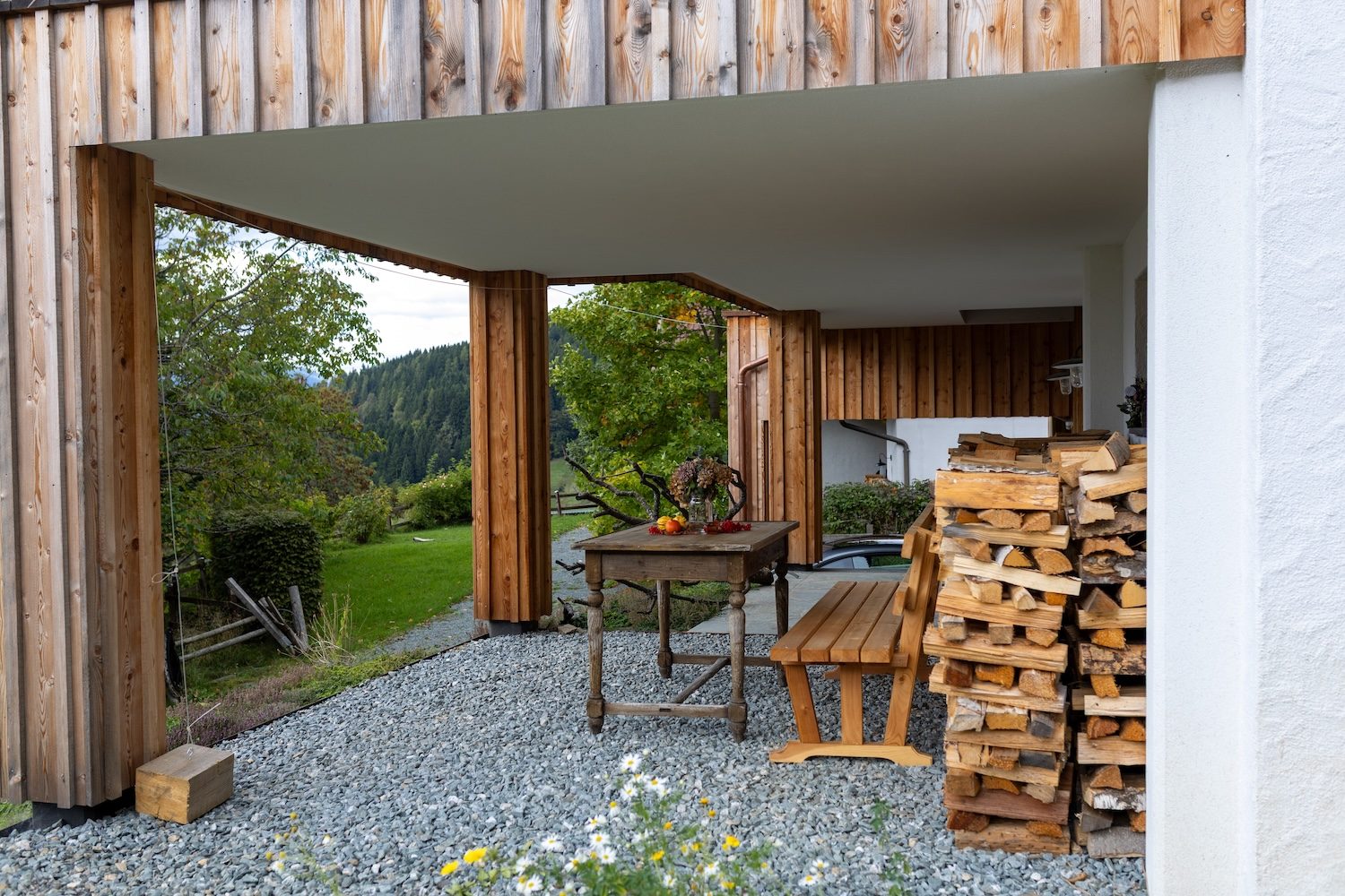 Überdachte Terrasse aus Holz mit altem Tisch, Bank und Blick ins Grüne