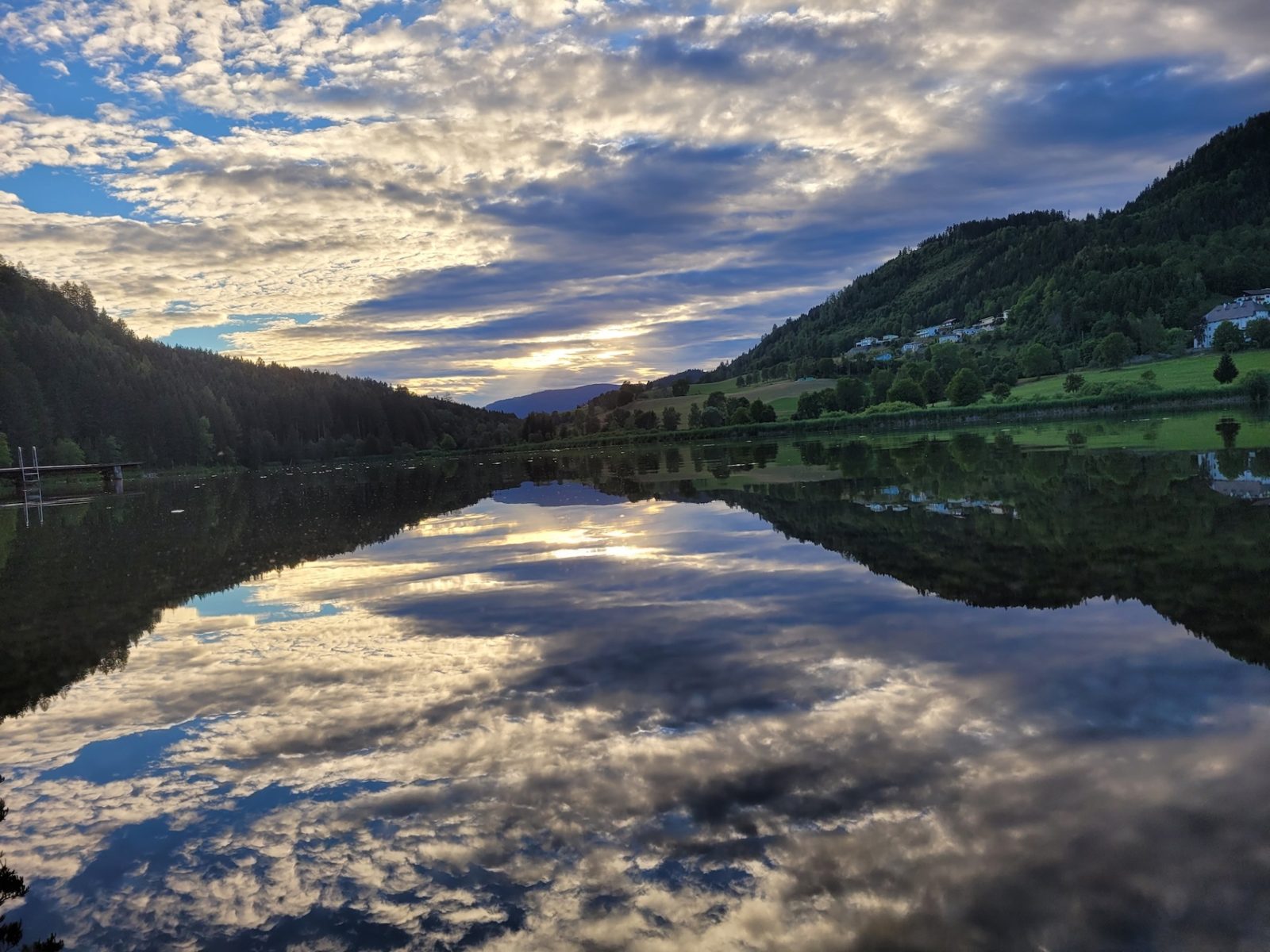 Spiegelnder Urbansee am Abend mit Wolken und Bergen